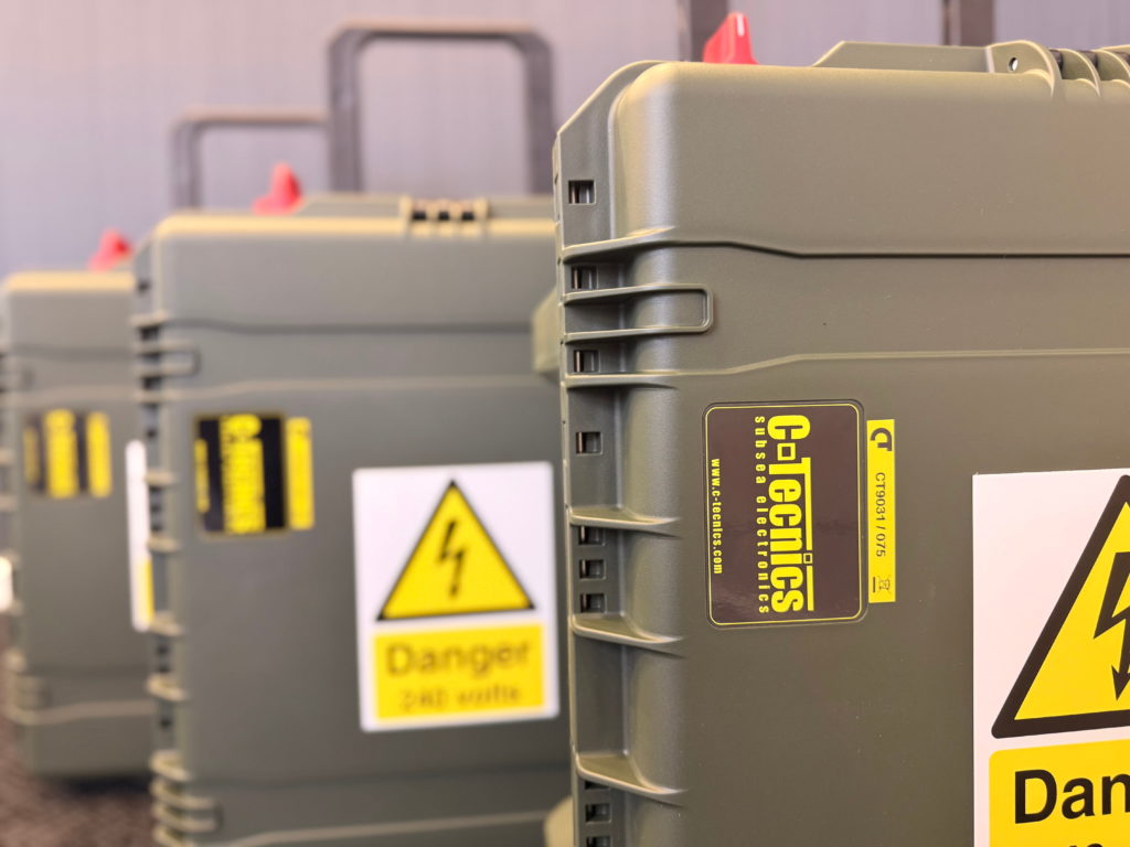 Close-up of stacked C-Tecnics rugged transit cases with branded labelling and 240 volt warning signage.